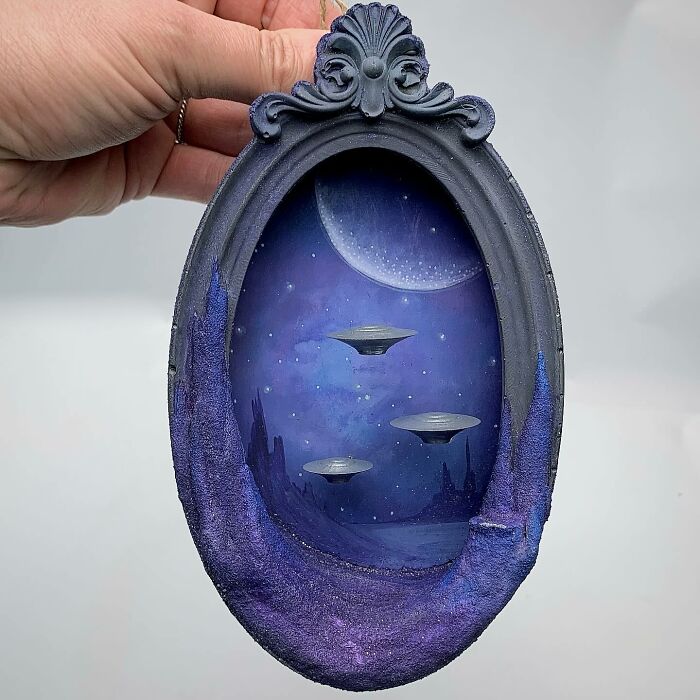 Alien-themed diorama by Caroline Dewison featuring a moonlit scene with UFOs in a decorative frame.