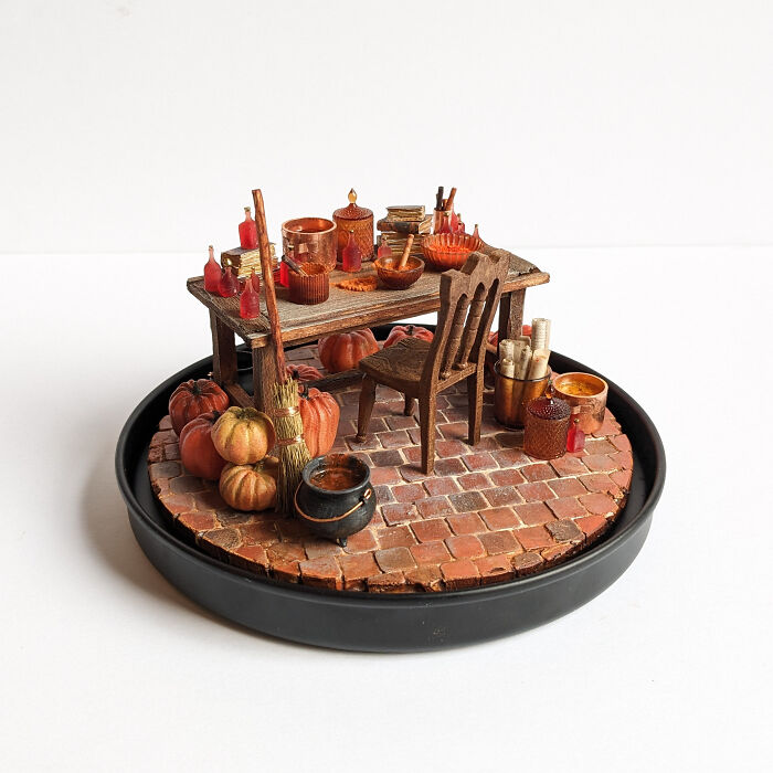 Miniature scene by Tamar Cohen featuring a tiny brick floor with a table, pumpkins, and various small objects.