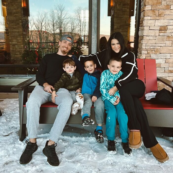 Family sitting on a bench in the snow, mom and dad with three kids, enjoying winter outside a rustic building. Family sitting on a bench in the snow, mom and dad with three kids, enjoying winter outside a rustic building.