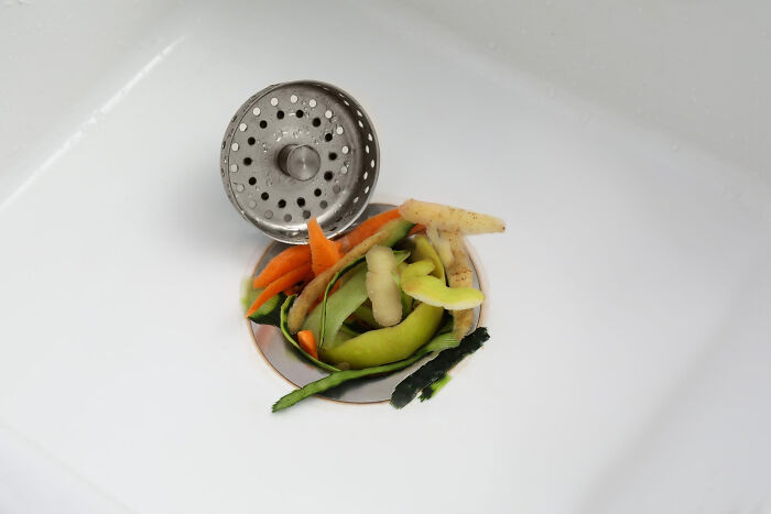 Sink with vegetable peels and strainer, highlighting an American kitchen habit.