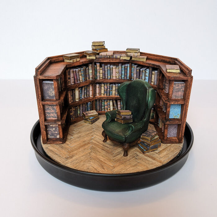 Miniature library scene by Tamar Cohen, featuring a green armchair and bookshelves, creating a tiny world atmosphere.