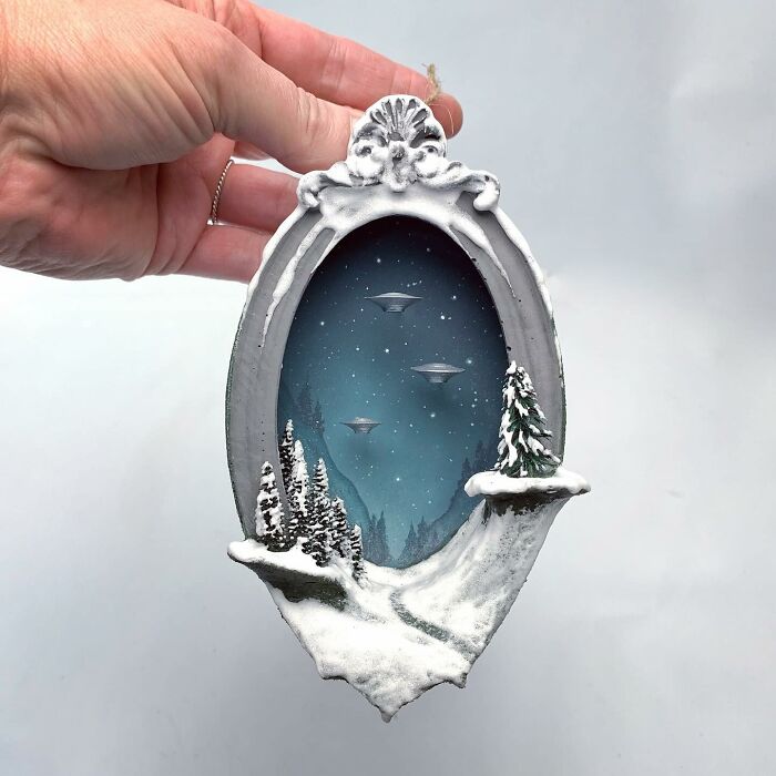 Hand holding a diorama featuring UFOs and a snowy landscape, perfect for alien enthusiasts.