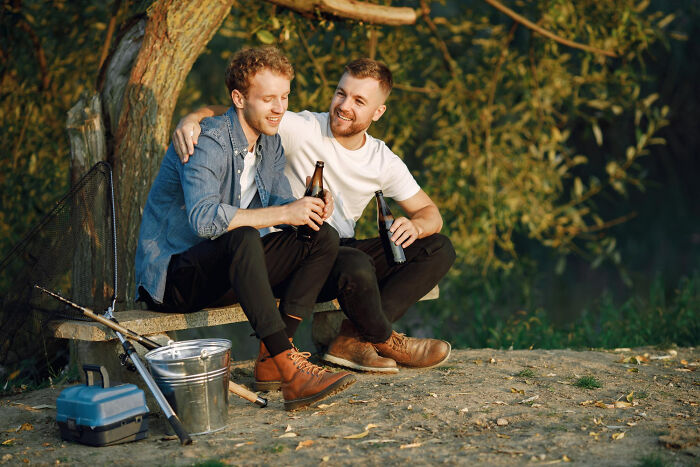 Two men sitting outdoors with drinks, highlighting humorous dating differences between genders.