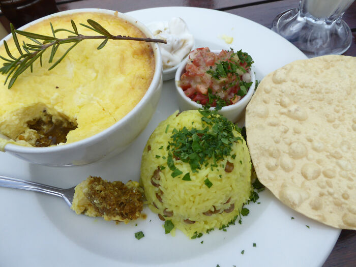 Bunny chow served with yellow rice, tomato relish, and papadum, highlighting top dish from different countries.