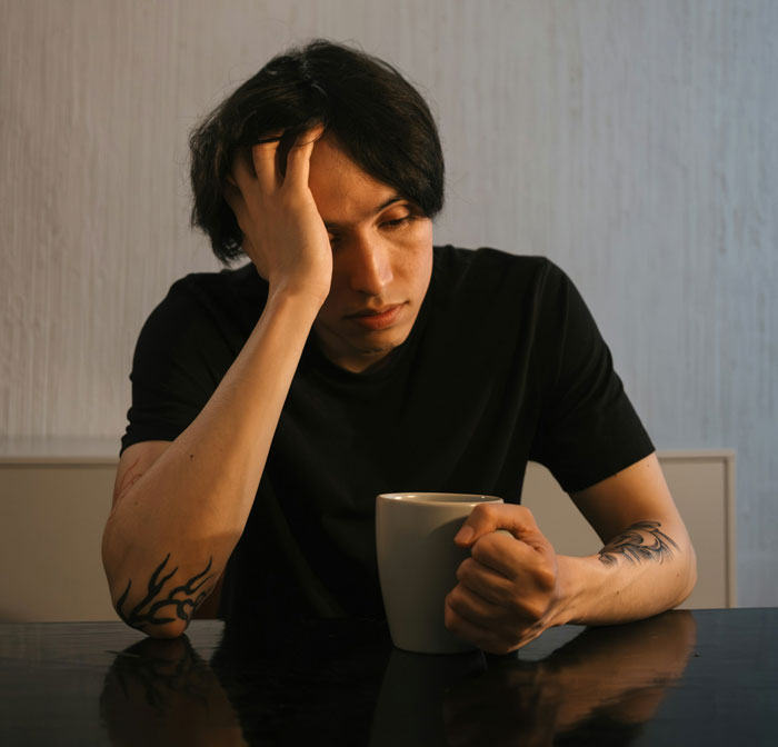 Man holding a mug, looking thoughtful after girlfriend defends against brother's prank. Man holding a mug, looking thoughtful after girlfriend defends against brother's prank.