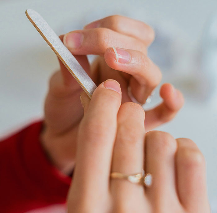 Close-up of a woman's hands filing nails, sparking a debate on patriarchy and nail length. Close-up of a woman's hands filing nails, sparking a debate on patriarchy and nail length.