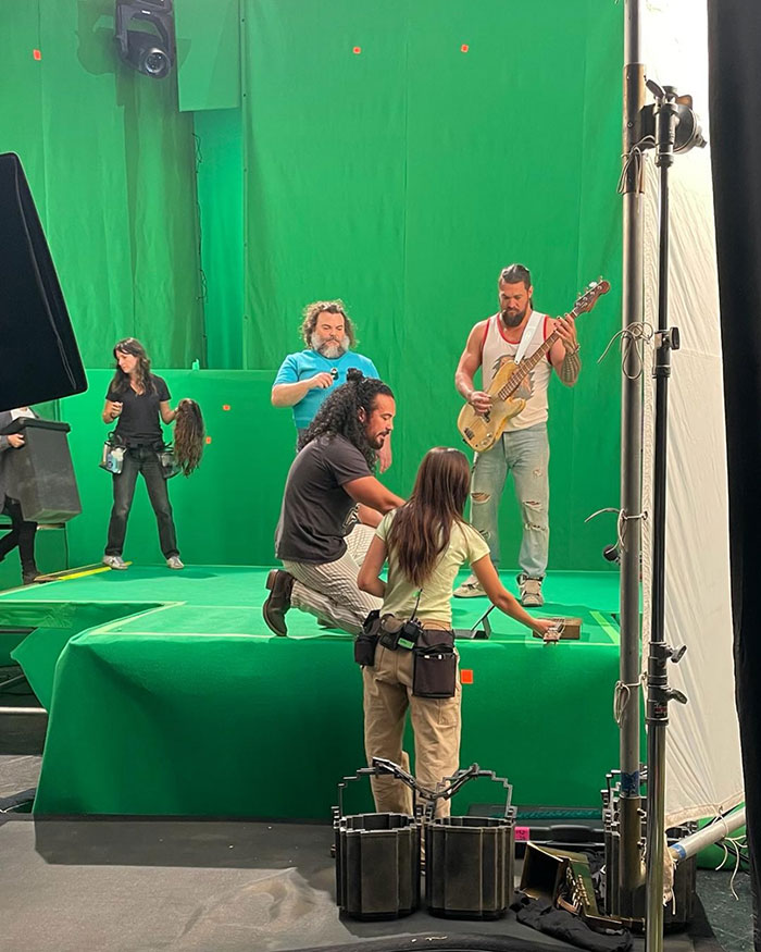 People on a green screen set, one holding a guitar. People on a green screen set, one holding a guitar.