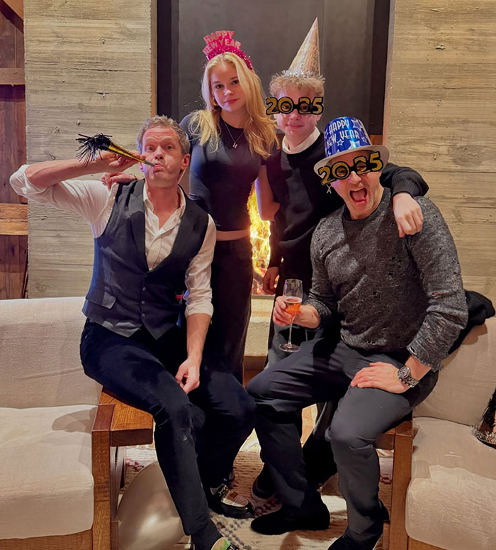 People celebrating New Year's Eve in festive hats, gathered around a fireplace, enjoying the evening together. People celebrating New Year's Eve in festive hats, gathered around a fireplace, enjoying the evening together.