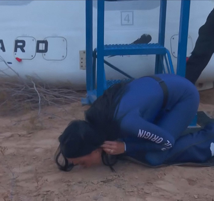 Person in a Blue Origin jumpsuit crouching on the ground, sparking conspiracy theories about the flight. Person in a Blue Origin jumpsuit crouching on the ground, sparking conspiracy theories about the flight.
