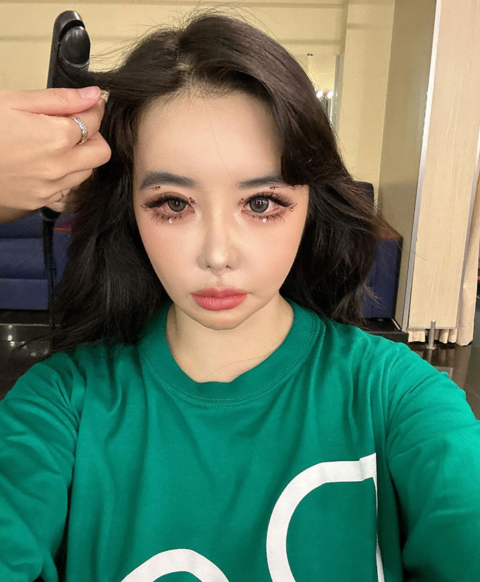 K-Pop star with drastic transformation amid plastic surgery rumors, wearing a green shirt, hair styled. K-Pop star with drastic transformation amid plastic surgery rumors, wearing a green shirt, hair styled.