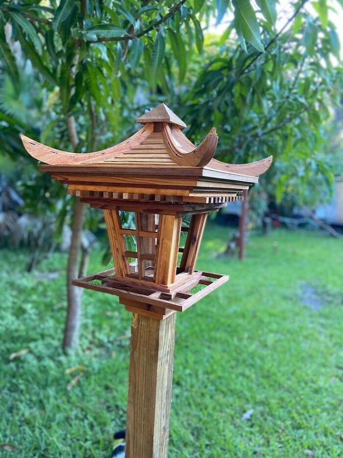 Woodworking project of a beautifully crafted wooden lantern with intricate roof design in a green garden setting.
