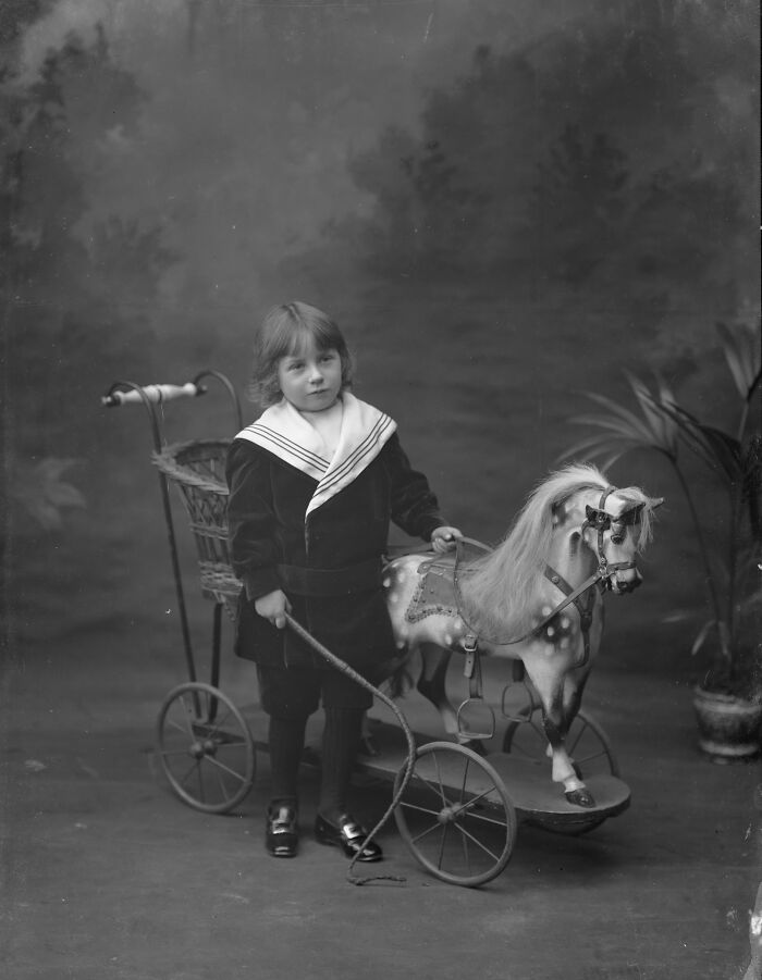 Vintage black and white photograph of a child with a toy horse and cart, rare photographs rescued from glass negatives.