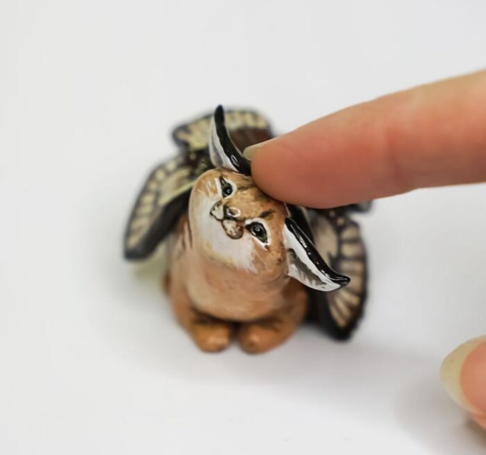 Pocket-sized animal figurine with wings being touched by a finger.