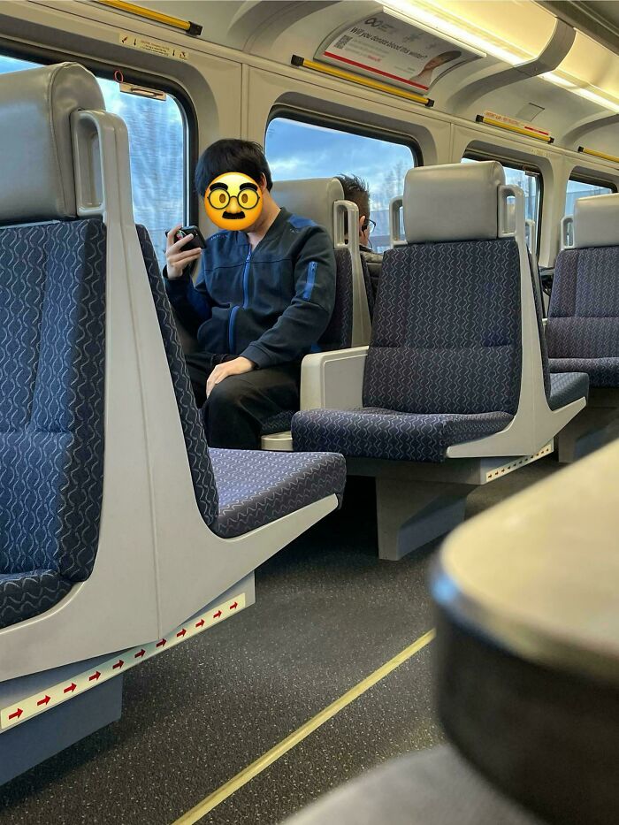 Person on train with shocked emoji over face, showcasing lack of self-awareness.