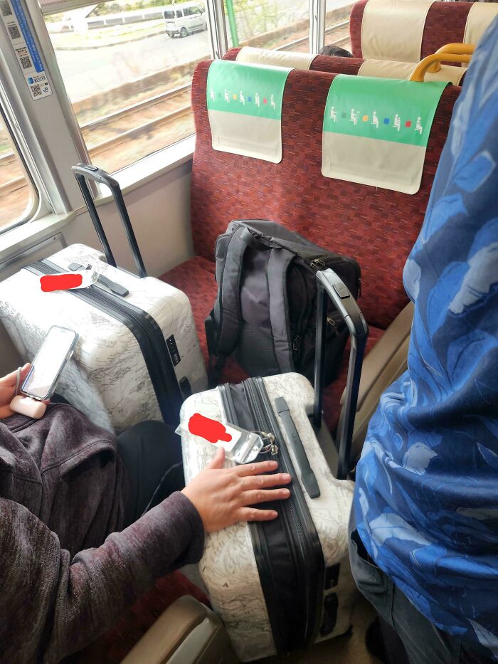 Person on train with suitcases occupying multiple seats, highlighting lack of self-awareness.