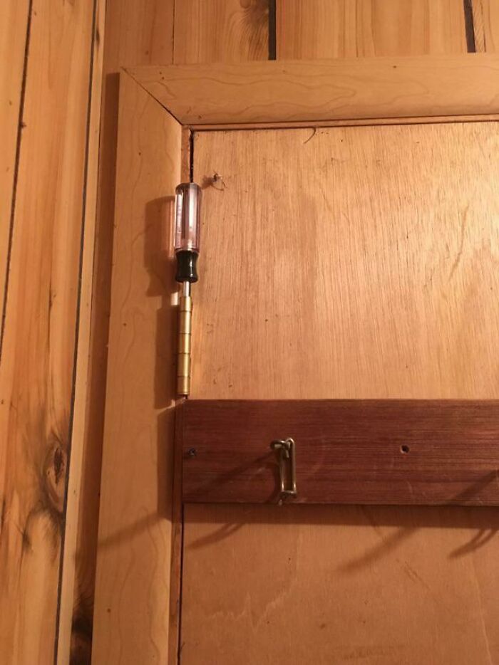 Screwdriver used as door hinge, showcasing humorous repair fail.