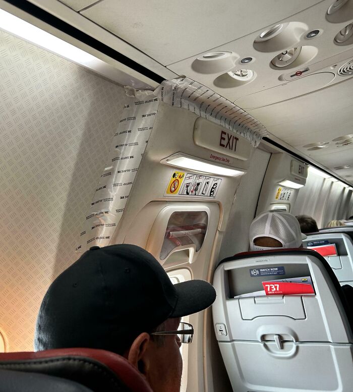 Airplane exit door with a taped repair attempt, highlighting failed repair effort.