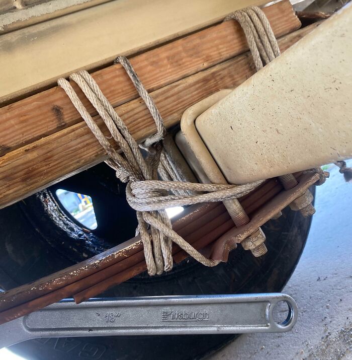 Failed repair using a wrench and ropes on vehicle suspension.