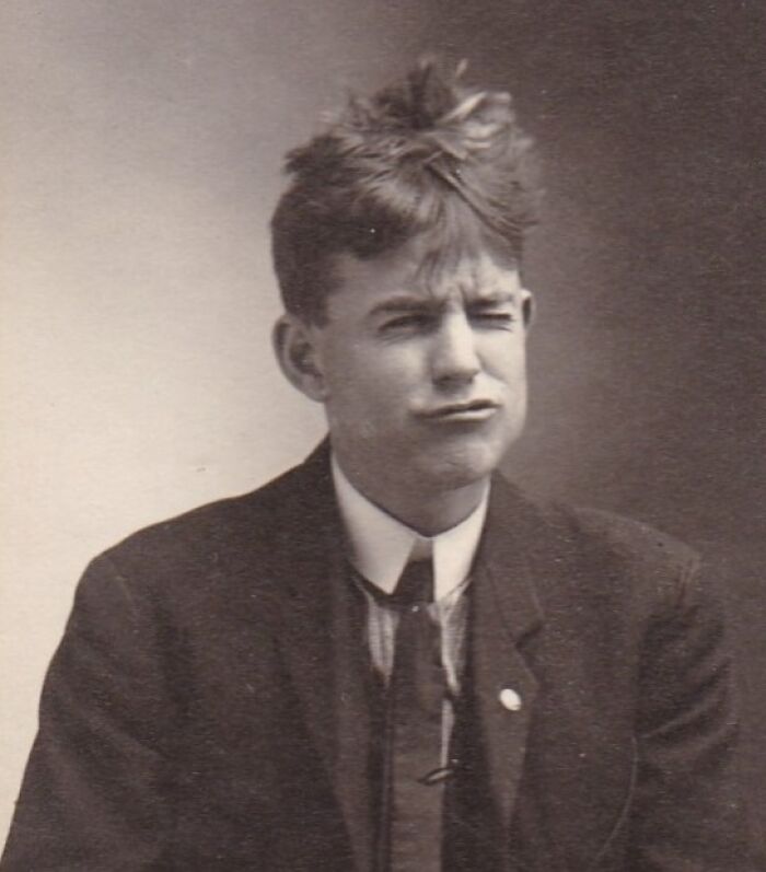Vintage photo of a man with a quirky hairstyle, wearing a suit and making a playful face.