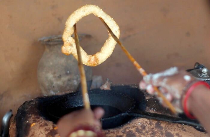 A person cooking a traditional top dish over a rustic stove, showcasing different countries' culinary techniques.