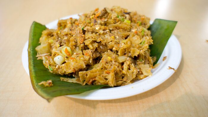 Top dish from a different country, served on a banana leaf, showcasing regional flavors on a white plate.