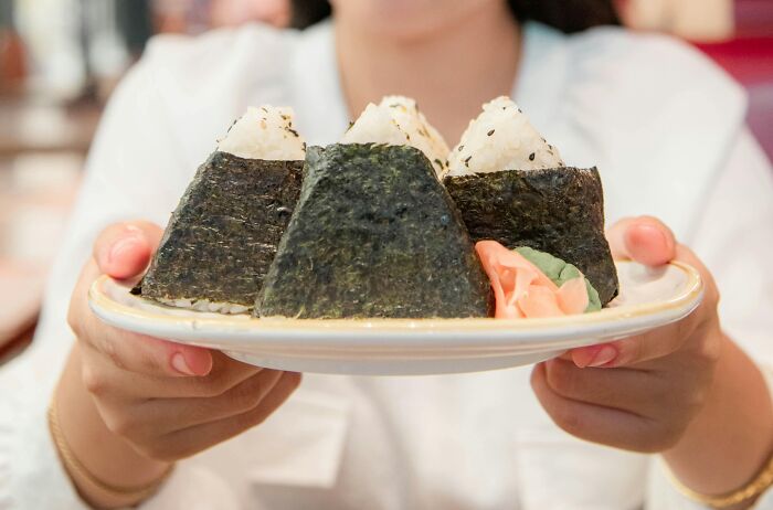 Plate of traditional rice balls from different countries' top dishes, served with pickled ginger.
