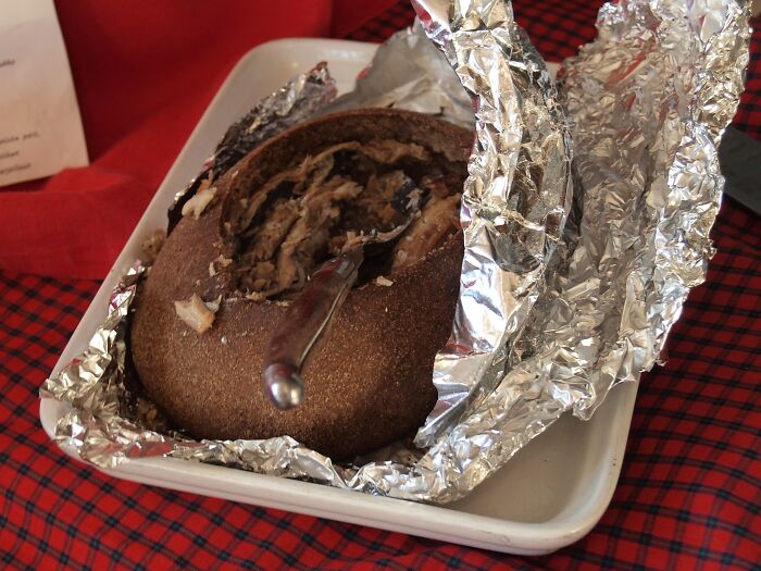 A traditional meat dish wrapped in foil, showcasing one of different countries' top dishes, served in a white tray.