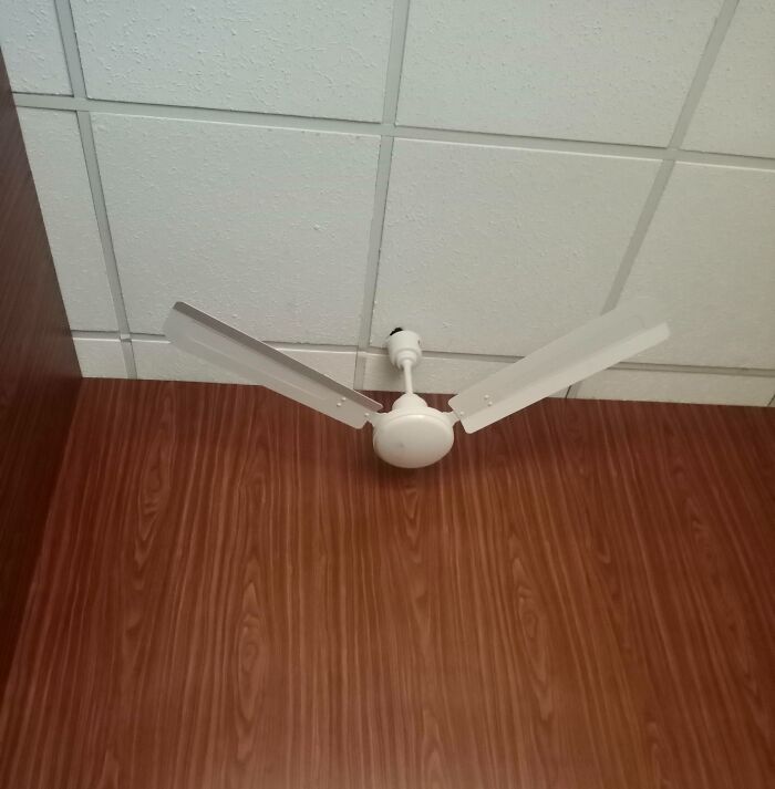 Ceiling fan with blades improperly installed vertically, highlighting repair fail.