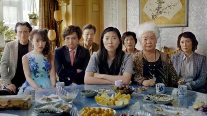 Group of people seated around a table, looking serious, in a scene from an emotional movie that may cause tears.