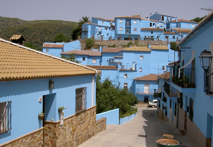 Colorful cityscape with blue houses on a hillside, resembling a real-life painting.