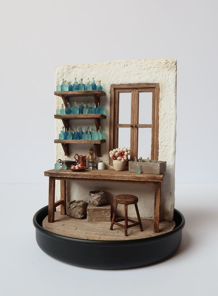 Miniature by Tamar Cohen depicting a tiny rustic room with shelves, bottles, and a stool.