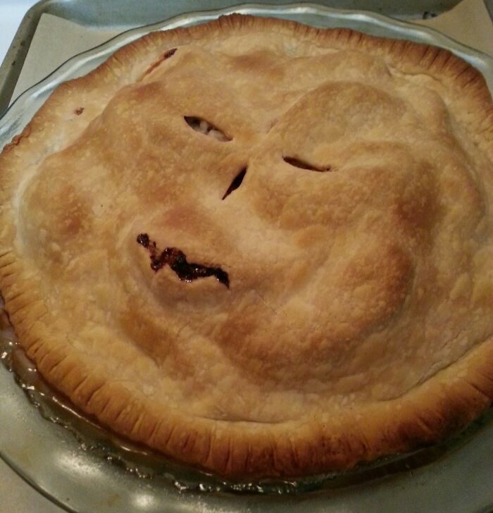 A pie with a humorous face-like pattern baked into the crust, showing a cooking mishap.