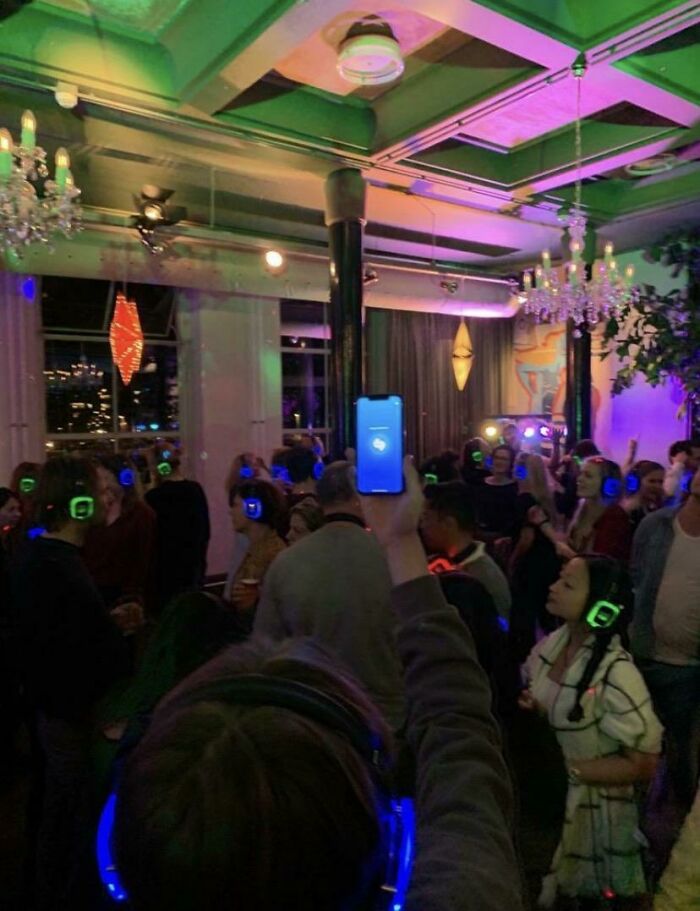 Silent disco party with colorful headphones and a person holding a phone up, capturing the lively atmosphere.