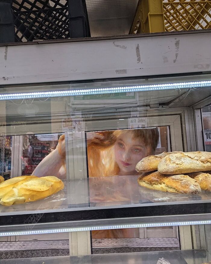Classical figure by Alexey Kondakov in modern bakery setting, with bread on display.