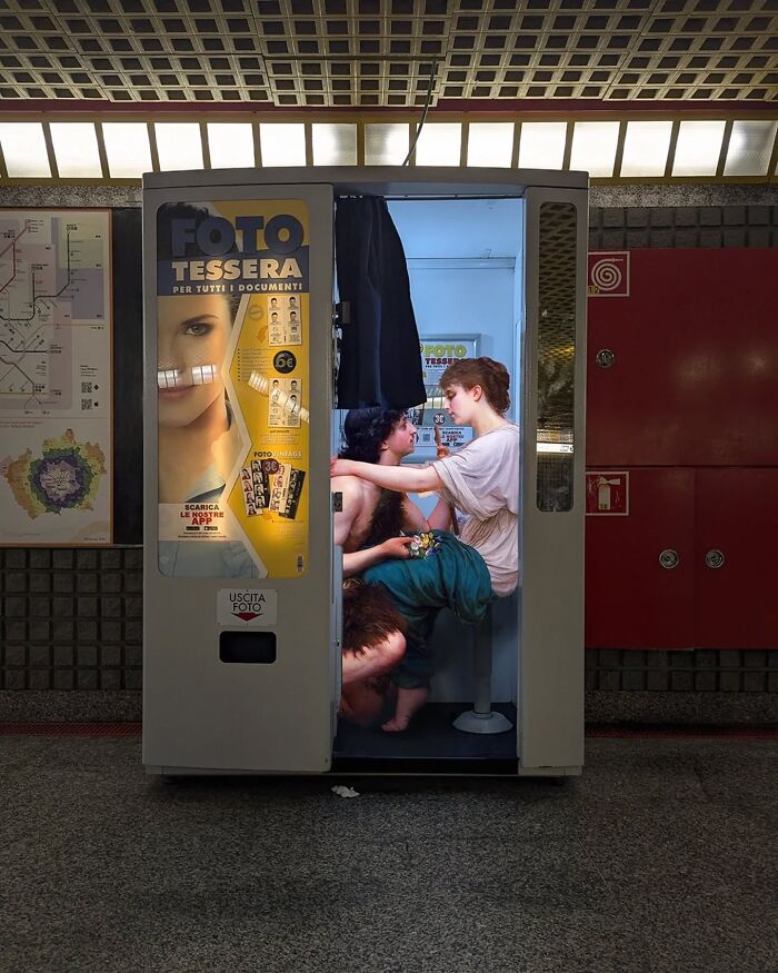Classical figures in a modern photo booth, blending art with contemporary urban setting.