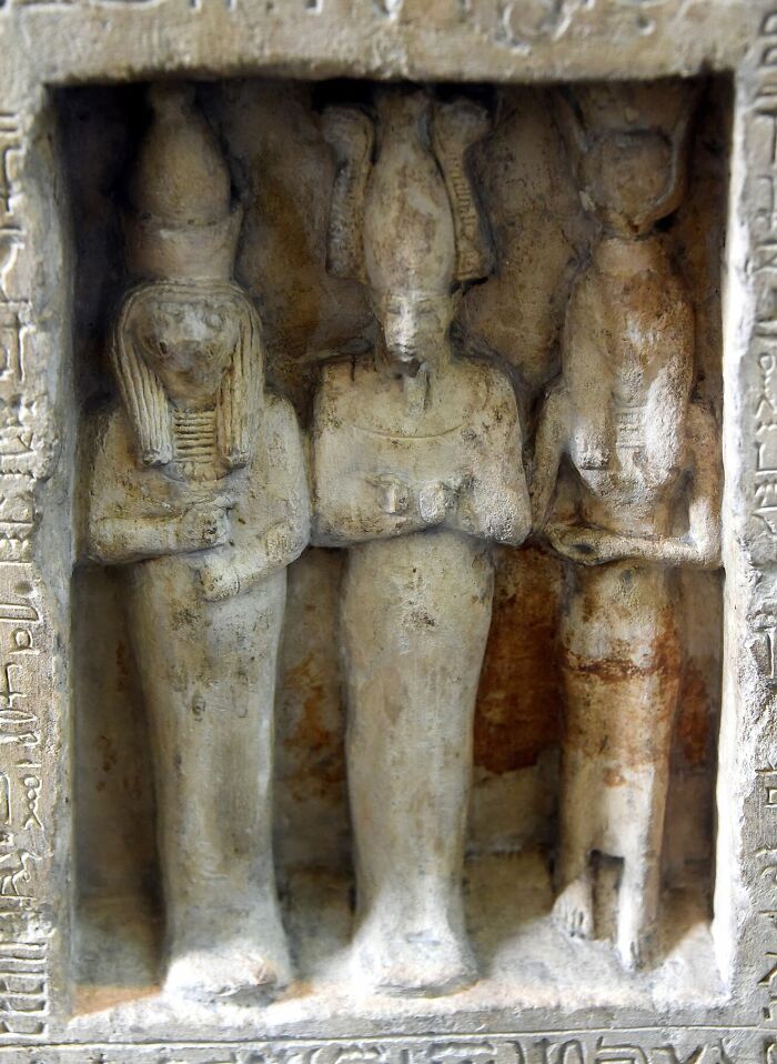 Ancient stone sculpture depicting a triple threat deities group with three gods standing side by side.