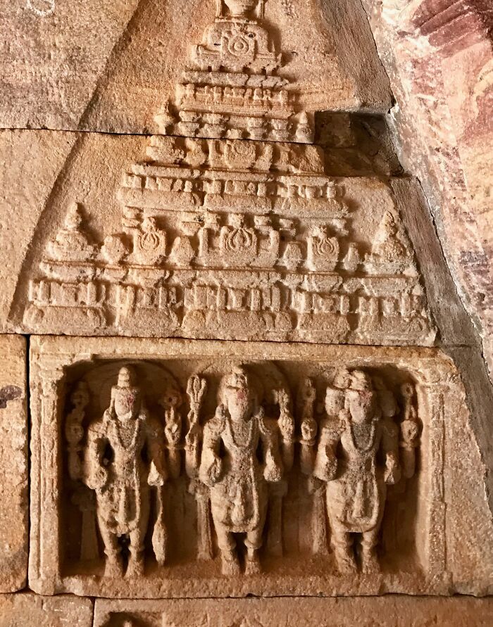 Ancient stone carving depicting a triple threat deities group in a historic temple wall relief artwork.