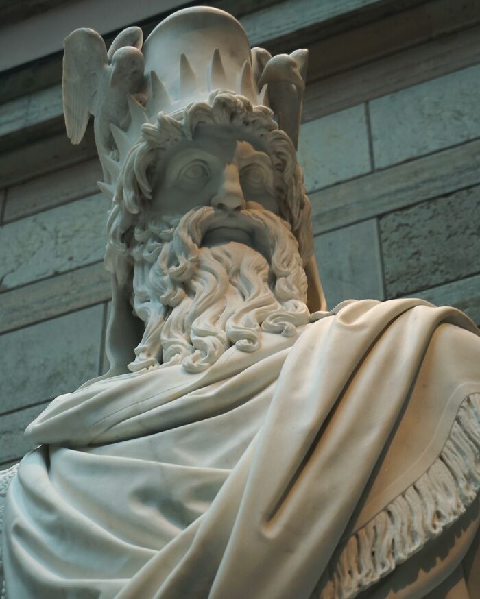 Close-up of a detailed marble statue of a bearded god, representing one of the triple threat deities from ancient mythology.