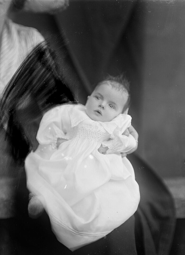 Black and white rare photograph of a baby in a white dress, rescued from glass negatives, showcasing history restored.