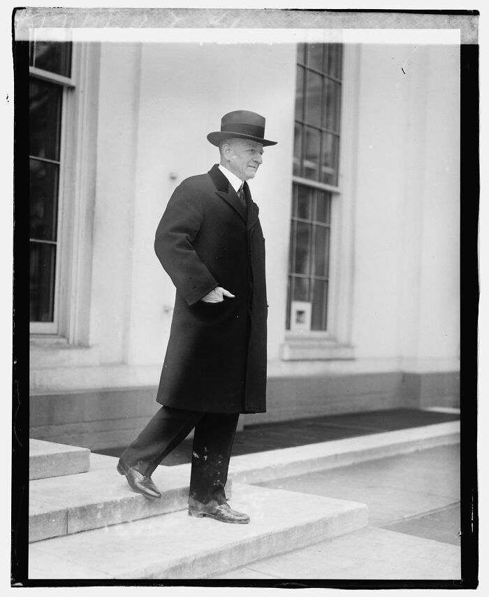 Black and white rare photograph of a man in a coat and hat standing on steps, restored from glass negatives.