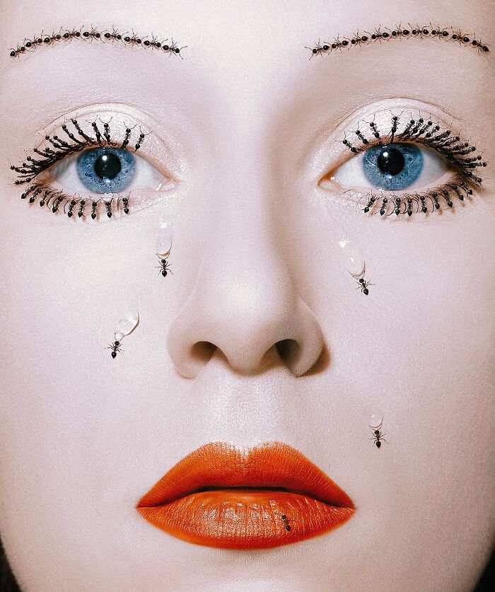Surreal self-portrait with vivid orange lips, blue eyes, and ants as eyelashes and tears in a dreamlike Photoshop creation.