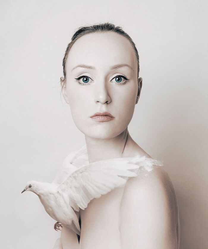 A surreal self-portrait showing a woman with a calm expression and a white bird perched on her shoulder.