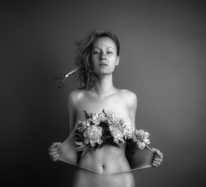 Artist's surreal self-portrait with flowers, scissors in hair, exploring dreamlike themes using Photoshop.