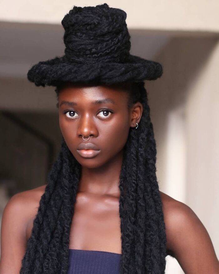 Woman with intricately styled hair sculpture, wearing a nose ring and strapless top, displaying artistic hair creativity.