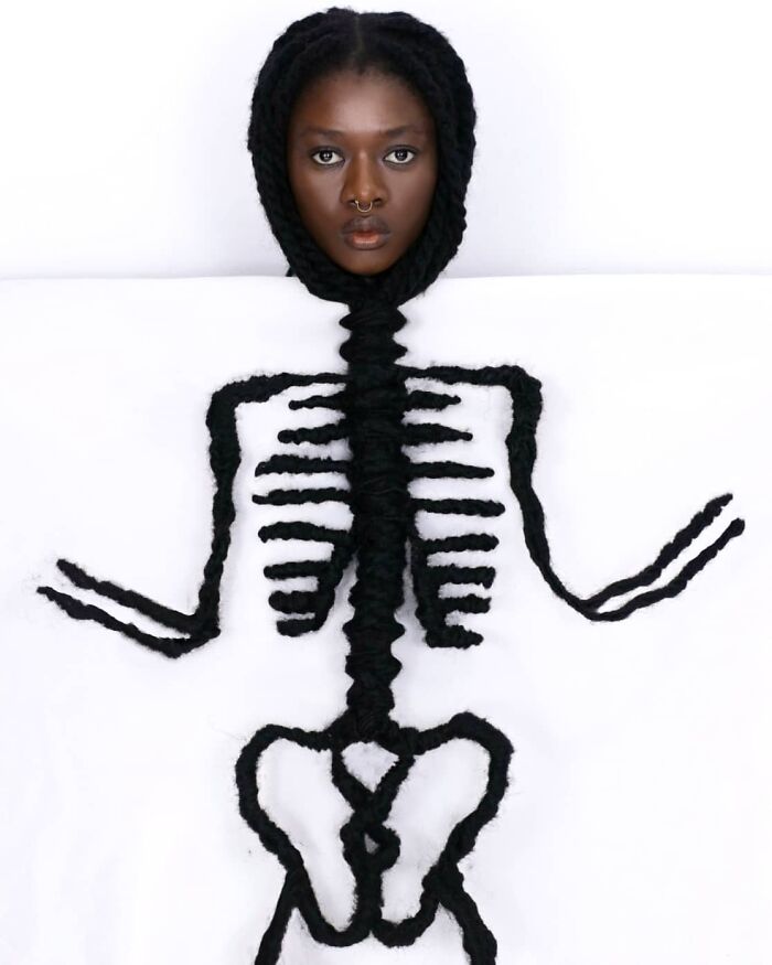 Hair sculptures forming a skeleton design around a female artist's face, showcasing artistic creativity.