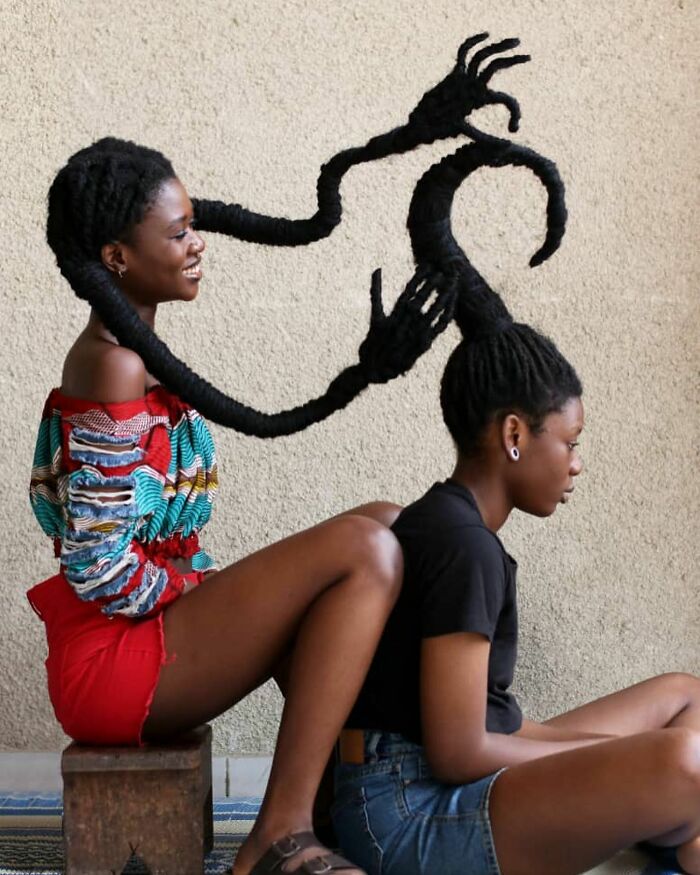 Artist creating hair sculptures, depicting intricate designs with long braids on two seated women.