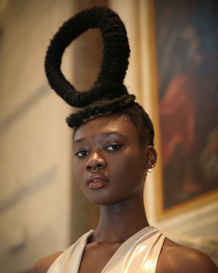 Woman with a hair sculpture design, forming a large spiral on top of her head.