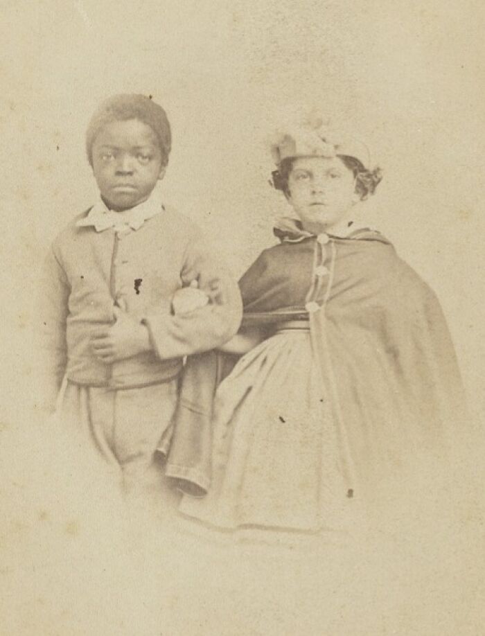 Two children dressed in period clothing, showcasing the strength of African Americans in a historic photograph.