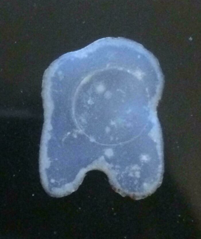 Unremarkable photo of a blue stone resembling a cartoon character on a black background, oddly entertaining.