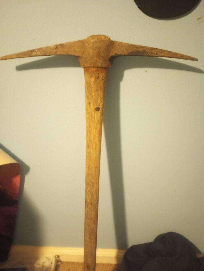 Old rusty pickaxe leaning against a wall in a room, one of the unremarkable photos that are oddly entertaining.
